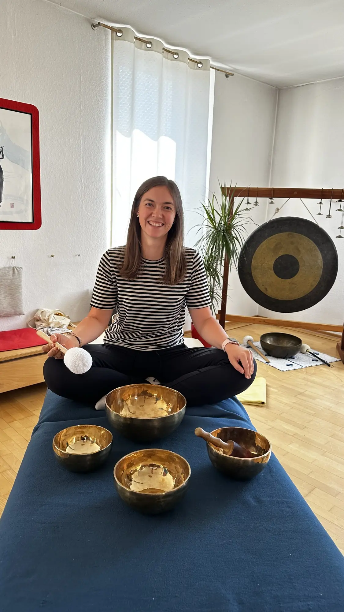 Laura mit einer goldenen Messing-Klangschale, ruhiger konzentrierter Ausdruck, natürliches Tageslicht.